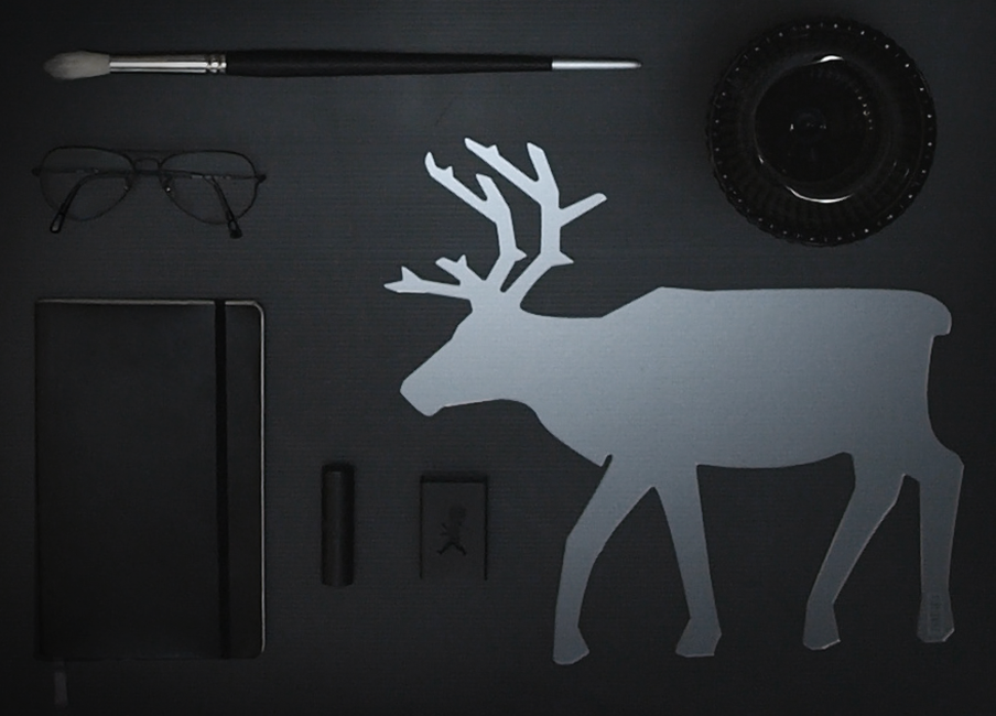 A flat lay of items in black with a reindeer silhouette in acrylic glass as the focal point