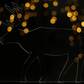 A silhouetted reindeer in acrylic glass against a backdrop of fairy lights 